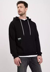 Czarna bluza z kapturem z białymi sznurkami, kieszenią kangurką i małym logo z przodu. Teksturowana tkanina, luźny krój i ściągacze w mankietach.