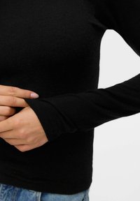 Svart långärmad topp i mjukt tyg, figurnära design med rundad halsringning, visar en jämn textur och med en något avsmalnande ärm.