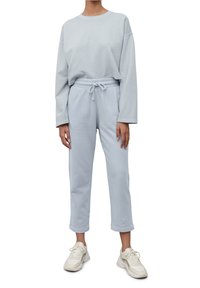 Světle modrá mikina s volným střihem a dlouhými rukávy, doplněná o odpovídající úzké tepláky s elastickým pasem a šňůrkou.