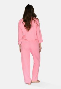 Set di pigiama rosa con maniche lunghe, vestibilità comoda e bordini azzurri su polsini e tasche, realizzato in tessuto morbido.