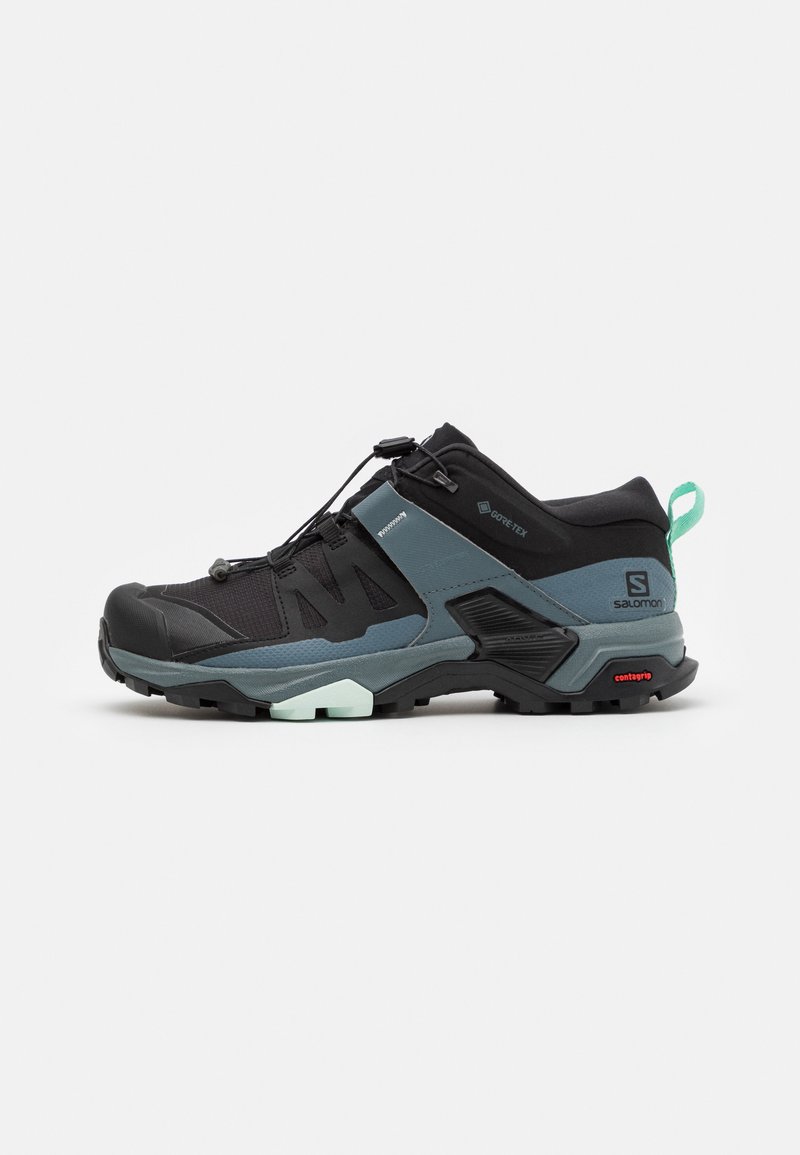 Vīriešu melni pārgājienu apavi ar GORE-TEX materiālu, izturīgu dizainu, gaiši zilu akcentu un strukturētu gumijas zoli, kas nodrošina labu saķeri.