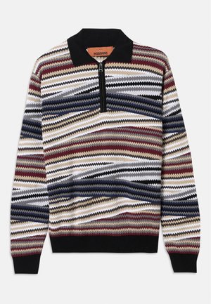 Strickjacke mit Reißverschluss, ausgestattet mit einem mehrfarbigen Zickzackmuster in den Farbtönen Rot, Blau, Schwarz und Beige; schwarzer Kragen und gerippter Saum.