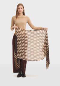 Écharpe à motifs marron et crème maintenue, présentant un design géométrique avec des bords frangés. Texture légère, forme rectangulaire.