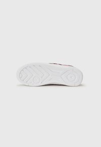 Semelle de chaussure avec une base en caoutchouc blanc, un motif texturé, une forme incurvée et des lignes de grip prononcées pour la traction.