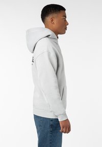 Hellgrauer Hoodie aus weichem Stoff mit Kängurutasche, gerippten Bündchen und einer verstellbaren Kapuze mit Kordelzug. Einfaches Design mit minimalen Details.