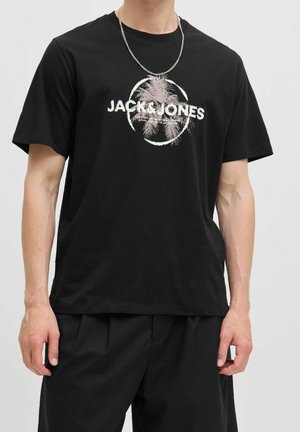 Homme portant un t-shirt noir Jack & Jones avec un motif de palmier et un collier en chaîne argentée, montré de la nuque aux hanches.