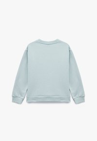 Sudadera azul claro de manga larga, con cuello redondo y puños y dobladillo acanalados. Textura suave, diseño informal, sin logotipos ni patrones visibles.
