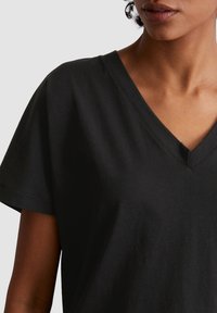 Zwarte V-hals T-shirt van zachte katoen, met korte mouwen en een relaxte pasvorm, met zichtbare stiksels langs de randen.
