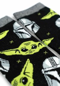 Calzini neri con motivi gialli e bianchi di un personaggio con grandi orecchie e un casco, tessuto a maglia testurizzato con polsini grigi.