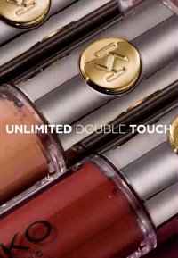 Due prodotti per labbra con packaging metallico argento e dettagli dorati. Uno è di un beige chiaro e l'altro è di un rosso intenso, etichettati "UNLIMITED DOUBLE TOUCH."
