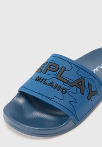Niebieskie klapki na płaskiej podeszwie z teksturowanym paskiem w kamuflażowy wzór oraz czarnym logo "REPLAY MILANO". Gładki materiał podeszwy.