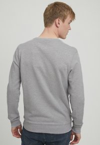 Grauer Pullover aus einem weichen Material, mit Rundhalsausschnitt, langen Ärmeln und einem gerippten Saum. Schlichtes Design ohne sichtbare Muster oder Akzente.