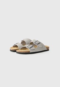 Sandale gri din suede cu două catarame argintii ajustabile, branț din plută și talpă din cauciuc negru. Design cu vârf deschis, cu o formă curbată.