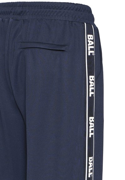 Pantalon de sport bleu marine avec une taille élastique, une poche latérale et des bandes blanches avec le logo "BALL" sur les côtés. Tissu lisse et texturé.