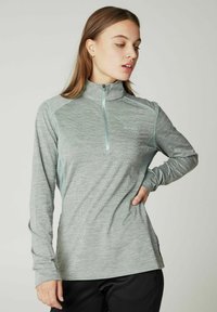 Grå langærmet zip-up skjorte med høj krave, der har et tekstureret mønster og kontrastfarvede lyseblå accenter langs sømmene.