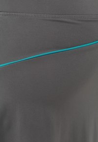 Pantalones cortos deportivos grises con una textura suave y una línea de acento turquesa a lo largo del costado. El diseño es aerodinámico con un ajuste entallado.