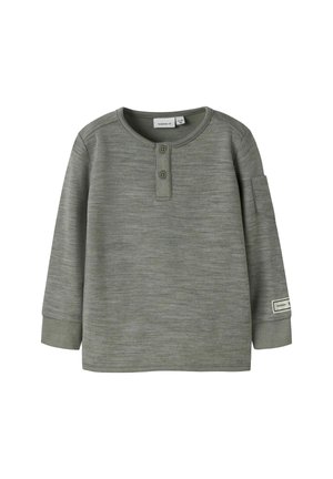 Chemise à manches longues vert foncé avec un col rond, une patte de boutonnage à deux boutons et une texture douce. Elle possède une poche à rabat sur la manche gauche.