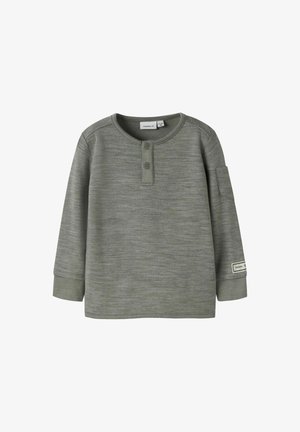 Ciemnozielona koszula z długim rękawem, okrągłym dekoltem, dwuprzyciskowym zapięciem oraz miękką fakturą. Posiada kieszonkę na lewym rękawie.