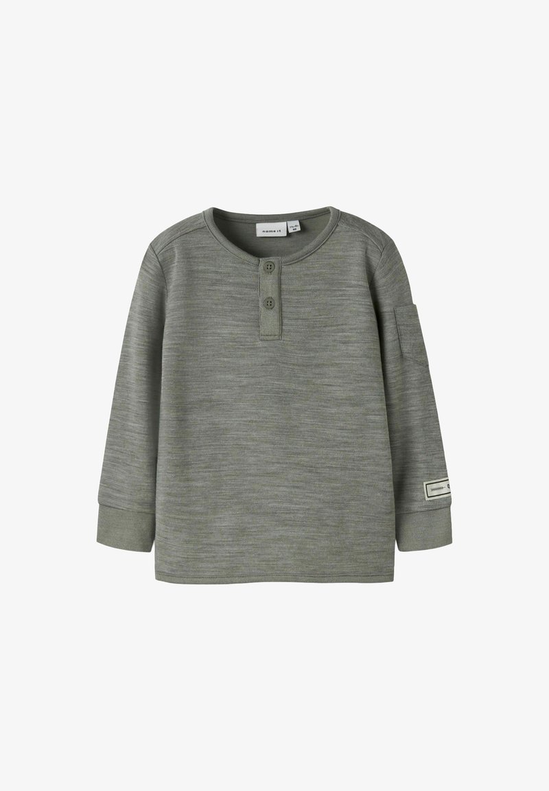 Dunkelgrünes Langarmshirt mit Rundhals, zwei Knöpfen und weicher Textur. Es hat eine aufgesetzte Tasche auf dem linken Ärmel.