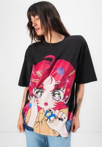 Black oversized t-shirt featuring a colorful graphic of a girl with red hair and starry eyes, set against a beige background.