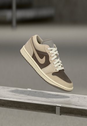 Sneaker beige e marrone in pelle strutturata e suede, con collo imbottito, lacci bianchi e suola in gomma. Logo iconico sul lato.