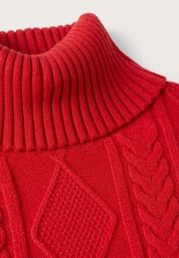 Pull rouge en tricot avec un col roulé côtelé. Présente des motifs torsadés et texturés sur le corps. Texture douce, aspect chaud.