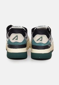 Sneakers con un design stratificato in grigio, nero e verde, caratterizzati da una suola in gomma testurizzata e un logo prominente sul tallone.