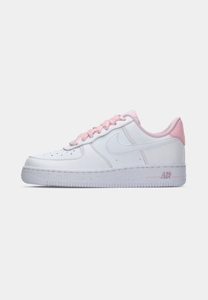 Baskets en cuir blanc avec des accents roses sur le talon et les lacets. Elles présentent une semelle texturée et des perforations pour une meilleure respirabilité.
