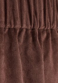 Tissu marron texturé avec des détails froncés, créant une apparence douce et drapée avec une surface lisse. Convient à différents types de vêtements.