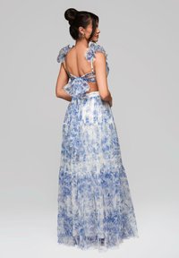 Blumenmuster Zweiteiler Kleid aus durchsichtigem blauem und weißem Stoff. Mit Rüschenträgern, einem Schleifendetail am Rücken und einem geschichteten Rock mit fließendem Silhouette.