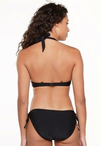 Schwarzes Bikini mit Halterneck-Bindung, schlichtes Design, verstellbare Bindebänder an den Seiten des Unterteils und eine glatte Textur.