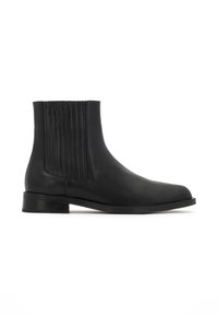 Stivaletto in pelle nera con cuciture verticali sui lati, silhouette snella, punta arrotondata e tacco basso impilato.