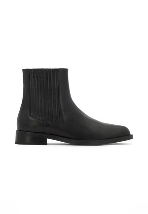 Black leather ankle boot featuring vertical stitching on the sides, slim silhouette, rounded toe, and low stacked heel.