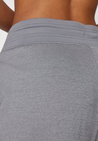 Leggings atléticos cinzentos apresentam um tecido texturizado com uma cintura em ribana e detalhes de costura mínimos. O design é ajustado ao corpo e sem emendas.