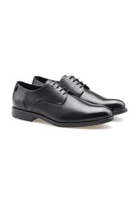 Schwarze Lederschuhe mit glatter Oberfläche, runder Zehenform, dezentem Nähen und einer Schnürdesign. Sie haben eine niedrige, strukturierte Gummisohle.