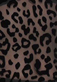 Material cu imprimeu de leopard negru, cu o suprafață texturată și pufoasă, pe un fundal transparent bej. Prezintă pete distincte de forme variate.