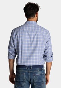 Blauw geblokt overhemd met opgerolde mouwen, gemaakt van lichte stof. De achterkant heeft een yoke en is gecombineerd met donkerblauwe jeans en een gevlochten riem.