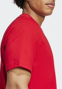 Červené bavlnené tričko s okrúhlym výstrihom a krátkymi rukávmi, s hladkou textúrou a uvoľneným strihom.