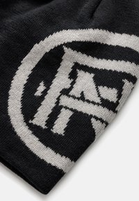 Czarna wełniana czapka z wyraźnym szarym logo. Materiał wydaje się miękki, o teksturowanym splotem i zaokrąglonym kształcie.