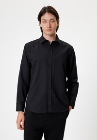 Zwarte lange mouwen overhemd met knopen, klassieke kraag, gladde textuur, voorkant placket en manchetten met één knoop. Effen kleur, geen patronen.