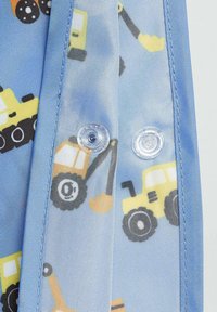 Blauwe stof met een patroon van gele bouwvoertuigen, met transparante drukknopen aan de voorkant. Zachte textuur, lichtgewicht materiaal.