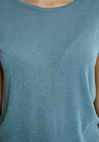 Tīrkultūru īsām piedurknēm džemperis ar apaļu izgriezumu, izgatavots no nedaudz teksturētas, spīdīgas auduma, kuram visā garumā ir smalks mirdzums.