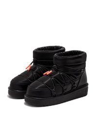 Botas de tobillo acolchadas negras con un acabado brillante, que cuentan con cordones elásticos y acentos en naranja. Suela gruesa de goma que mejora la durabilidad y la comodidad.