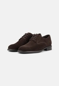 Bruine suède jurk schoenen met een gladde afwerking, ronde neus, vlakke zwarte zool en vetersluiting met dunne, bijpassende veters.