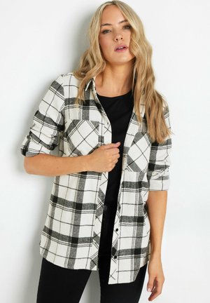 Sorte og hvide ternede flannel skjorte med lange ærmer, knaplukning, en brystlomme og et blødt, tekstureret stof. Sort top under.