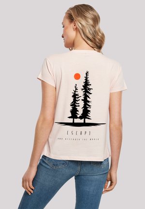 Helles rosa T-Shirt mit kurzen Ärmeln, das auf der Rückseite eine schwarze Grafik von zwei Pinienbäumen und einer roten Sonne zeigt, mit dem Text "FLIEH UND ENTDECKE DIE WELT."