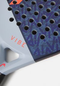 Smaiļošanas rakete ar zilu un pelēku virsmu, kurai ir teksturēts raksts un vairāki caurumi; uzdrukāts "VIBE" oranžā krāsā.