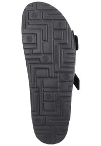 Black rubber shoe sole featuring a textured, patterned surface with spirals and geometric shapes, designed for grip and durability.