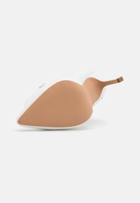 Weißer High-Heel-Schuh mit spitzer Zehe. Glattes Obermaterial, dünnes Design und eine braun gemusterte Gummisohle mit schmalem Absatz.