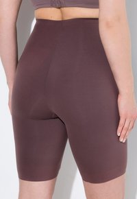 Bruna höga shaping-shorts gjorda av ett slätt, stretchigt material. Har en mitten-lårskärning med en sömlös design och minimal sömnad.